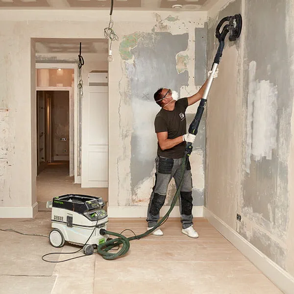 A painter machines the walls with the Festool long-reach sander