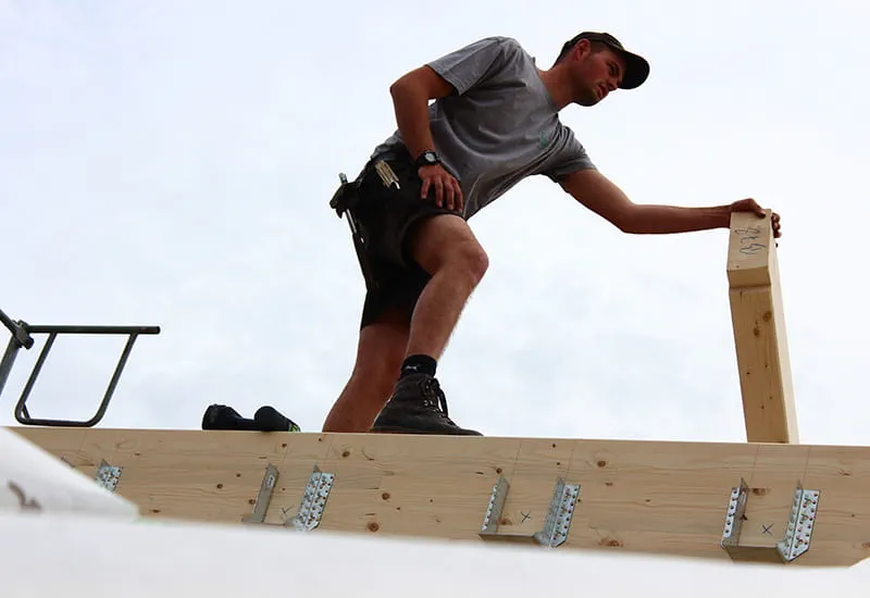 A carpenter put the roof beam in the right position.